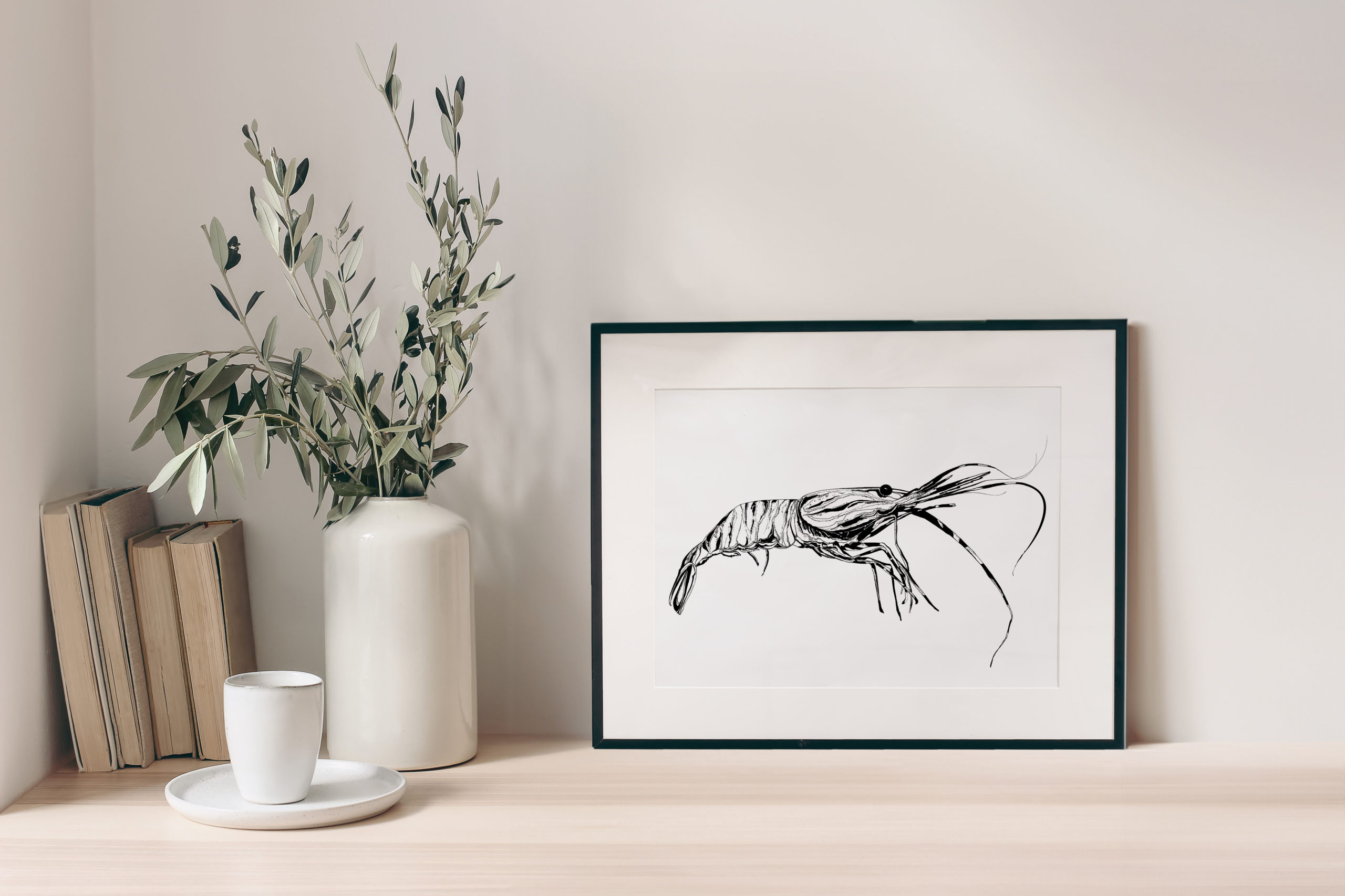 Breakfast still life. Cup of coffee, books and empty picture frame mockup on wooden desk, table. Vase with olive branches. Elegant working space, home office concept. Scandinavian interior design.